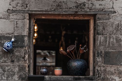 Free Artistic display of rustic clay pots and vases in a stone window frame, blending traditional and modern decor. Stock Photo