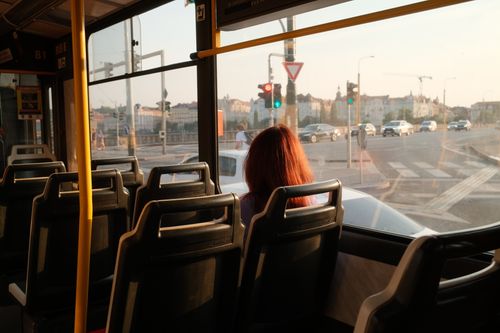 Free A solitary figure gazes out from a bus window, capturing the serene urban landscape at dusk. Stock Photo