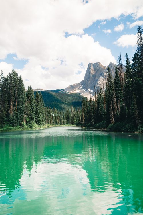 Free A tranquil emerald lake surrounded by mountains and forest in British Columbia, Canada. Stock Photo
