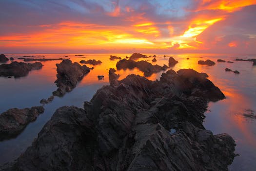 岩石海岸的日落景色壮丽，鲜艳的色彩在水面上倒映