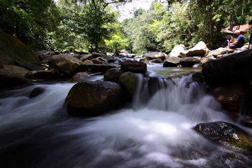 Man Sitting on Rock Near the Waterfalls