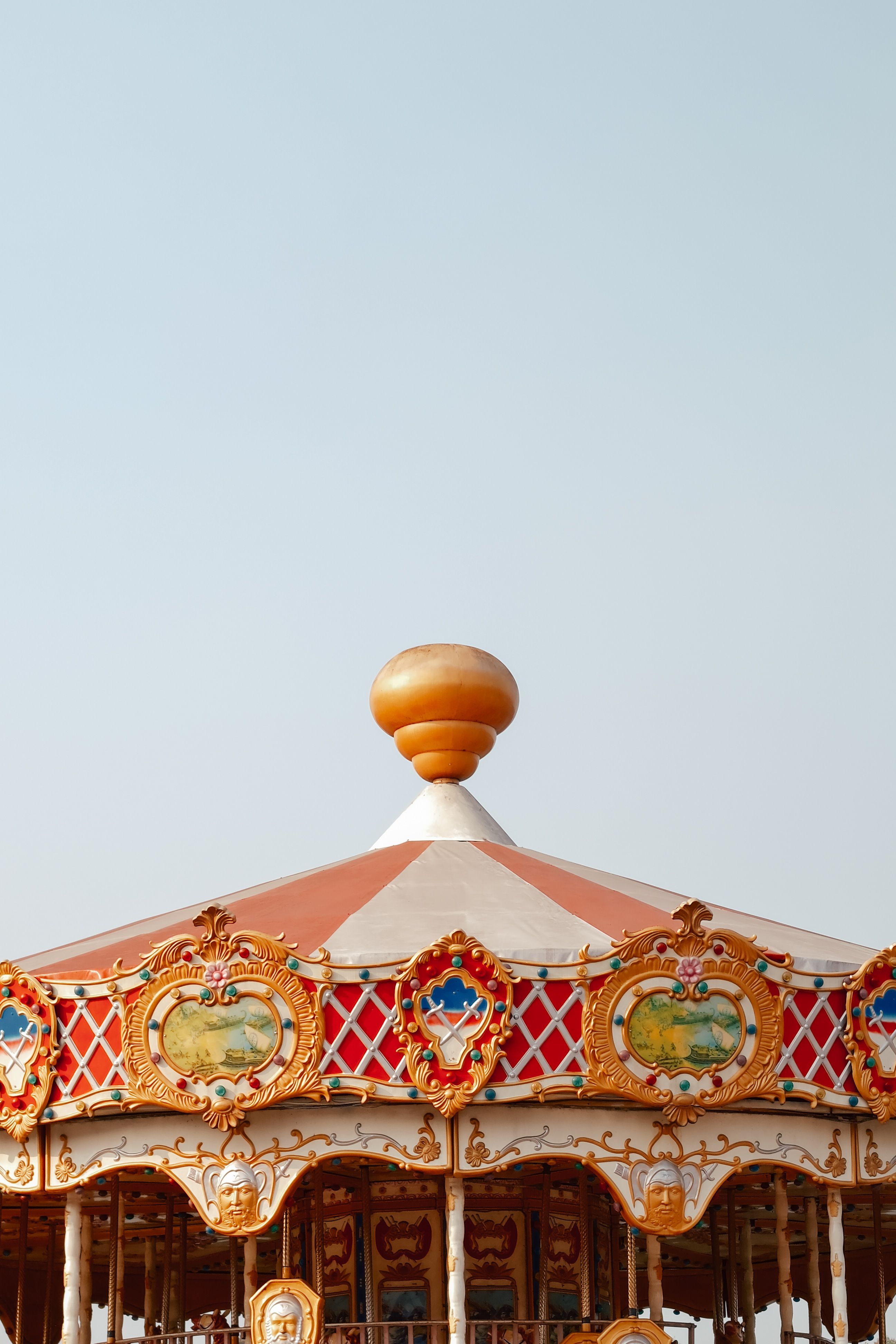 A colorful vintage carousel roof with intricate details against a clear sky, evoking nostalgia.
