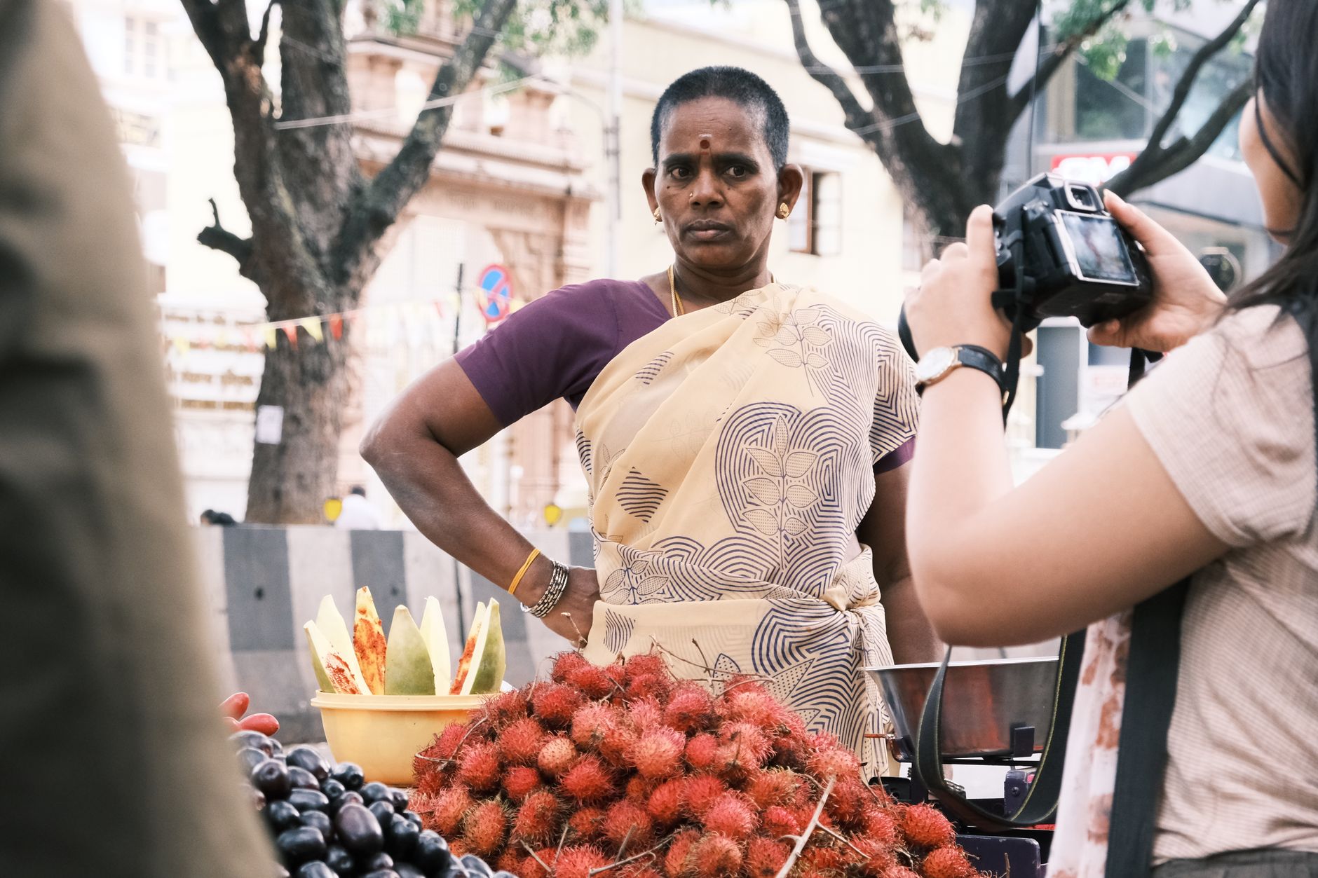 A local woman selling fresh rambutans and fruit at a street market in Bengaluru, India.