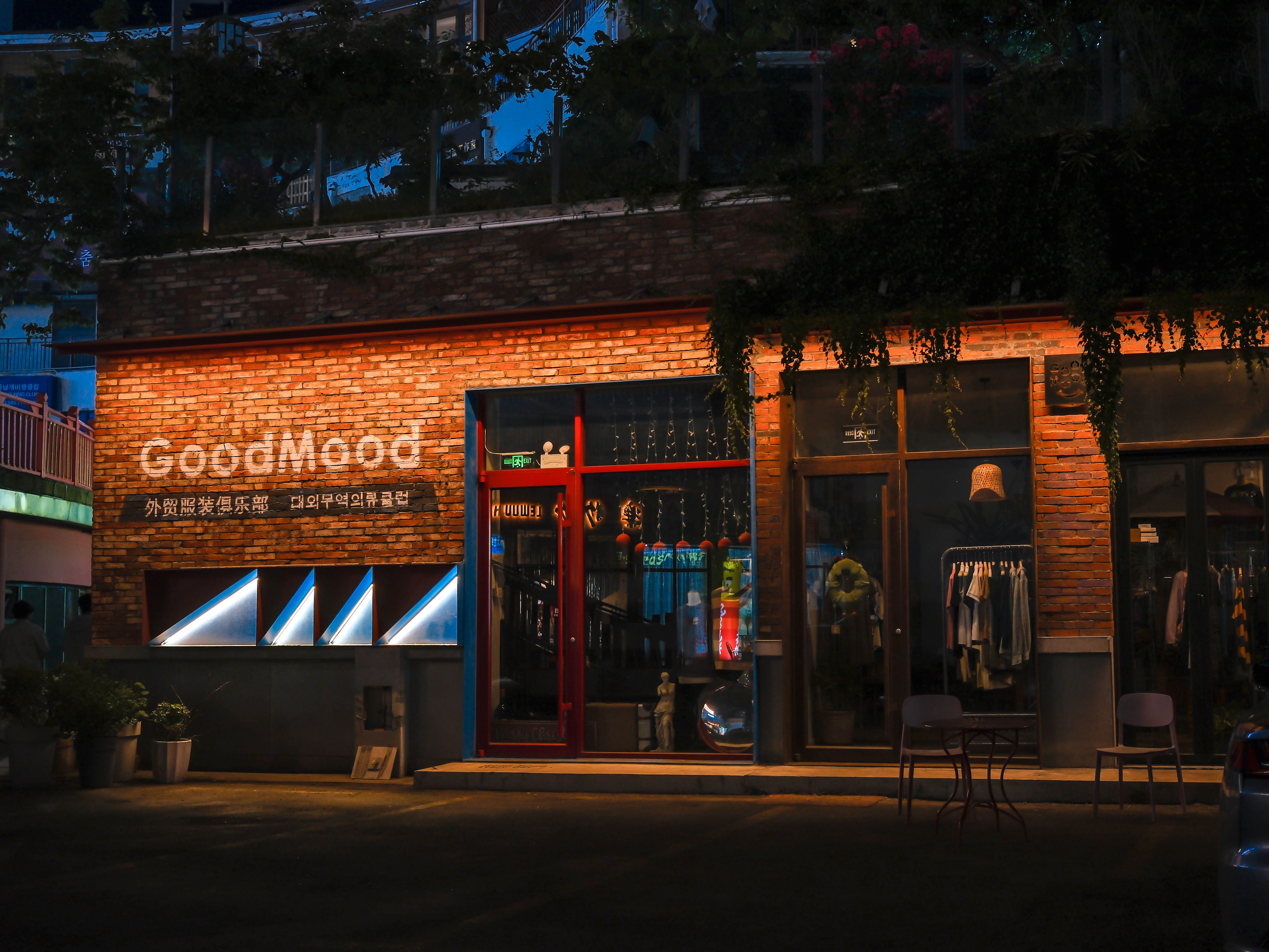 Charming boutique with warm brick facade lit at night, showcasing stylish interiors.