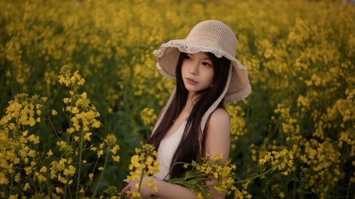 Free Young woman in a field of yellow flowers wearing a sun hat. Stock Photo