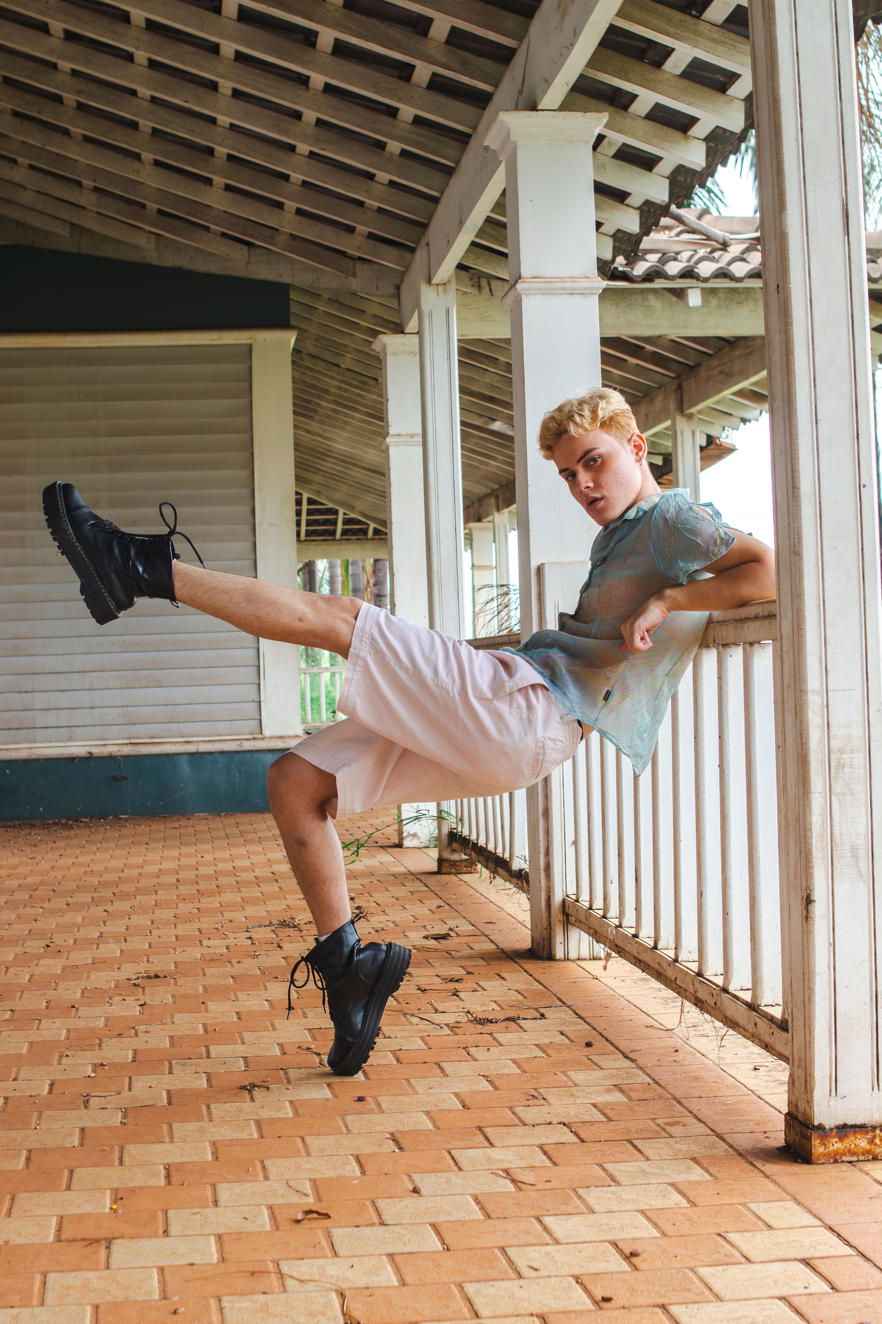 Young adult showcasing a stylish and relaxed pose on an outdoor terrace with brick flooring.