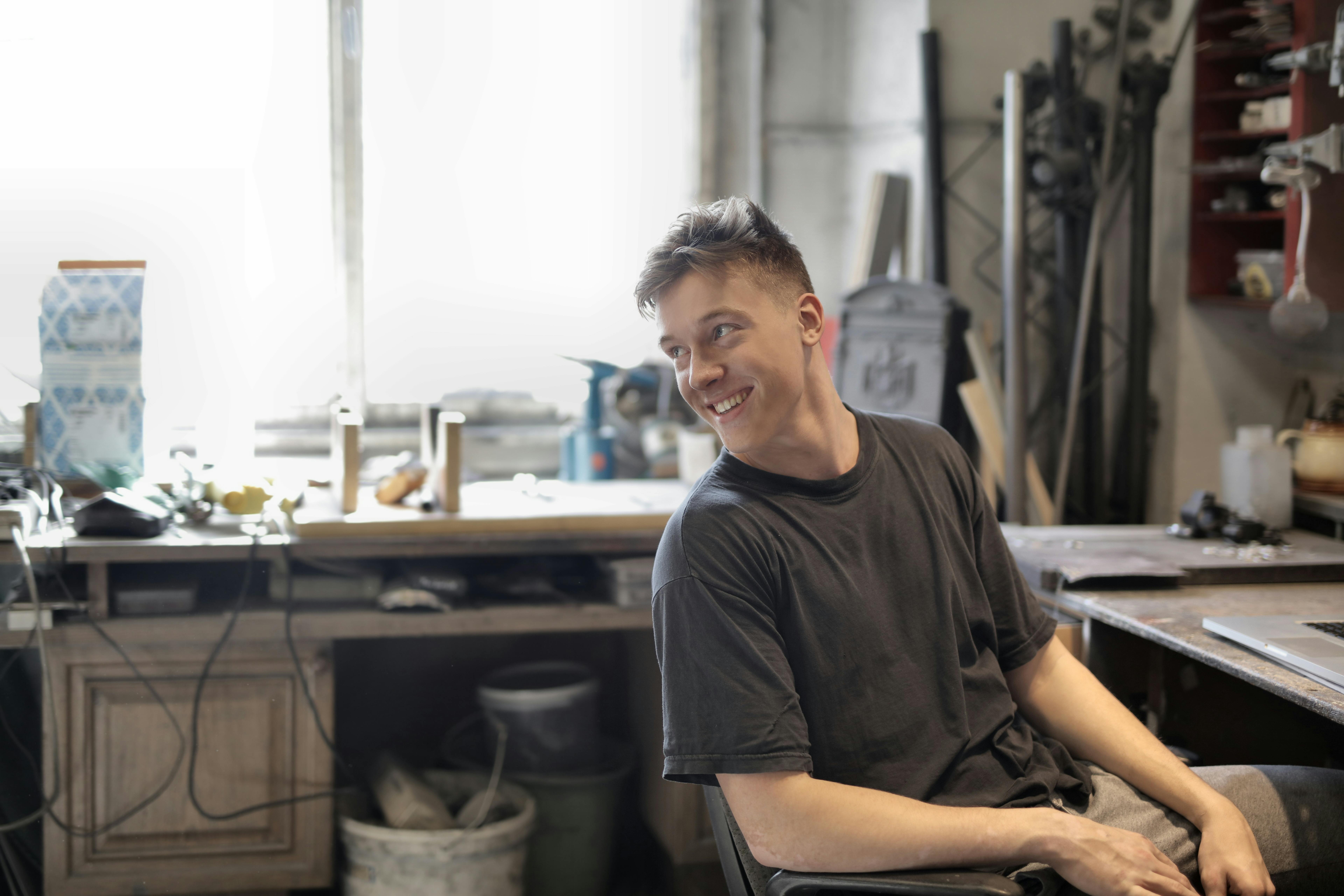 cheerful man sitting at table in workshop