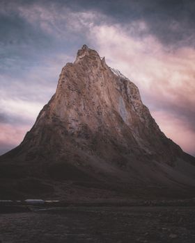 A towering mountain peak under a dramatic twilight sky, showcasing natural beauty and grandeur.