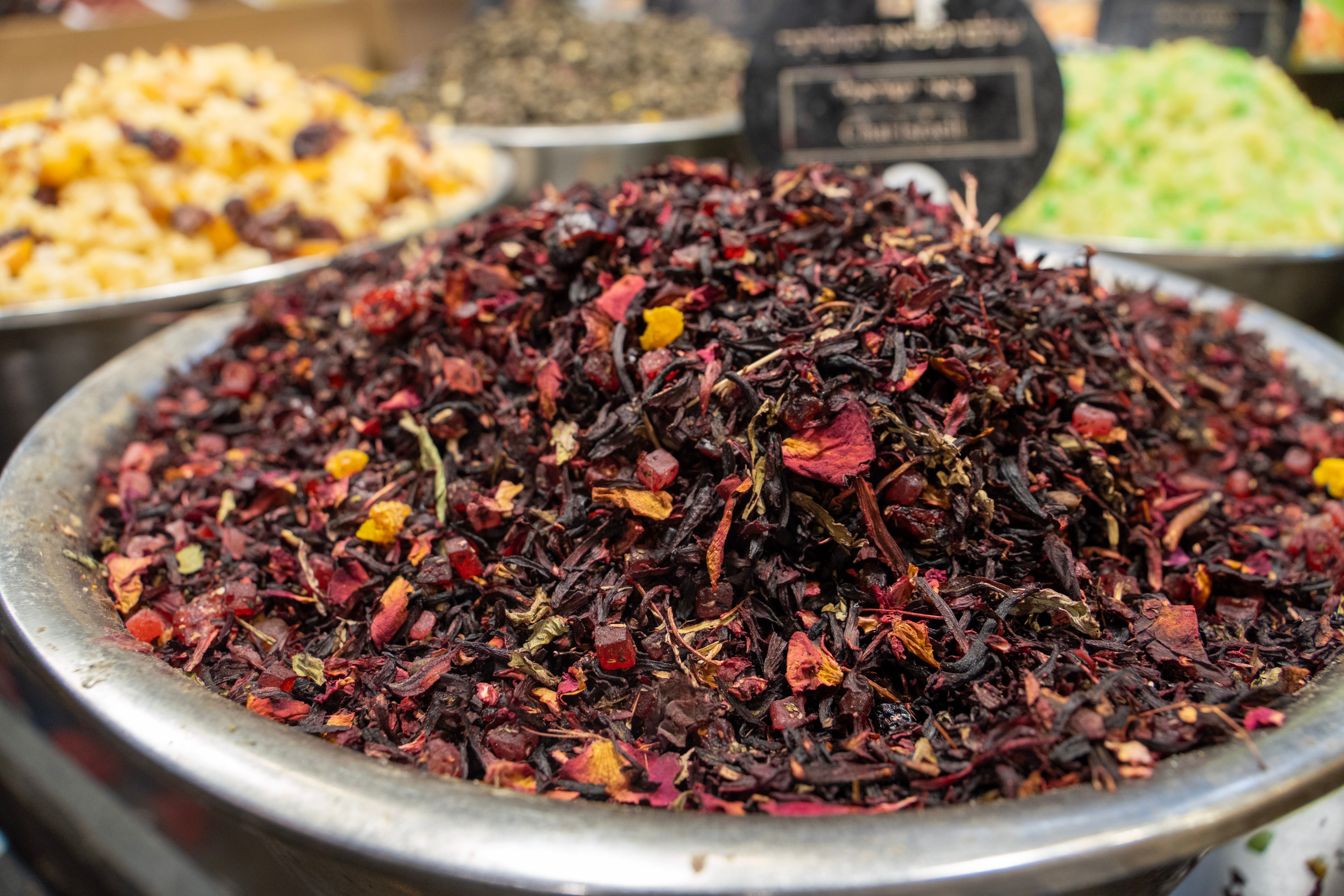 Vibrant dried hibiscus tea leaves in a metallic bowl at a spice market