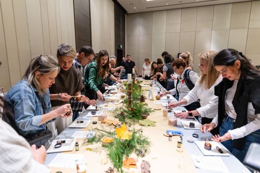 A diverse group of people engaged in a creative workshop indoors, focusing on arts and crafts.