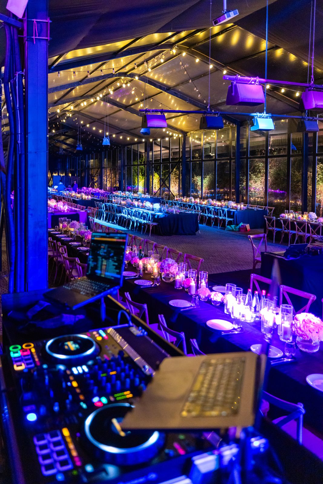 Vibrant indoor evening event with DJ equipment and elegantly lit tables