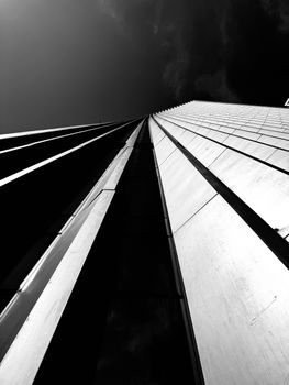 Dramatic black and white view of a modern skyscraper, emphasizing sleek lines and towering height.