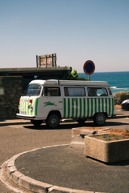 Free A classic camper van parked by the ocean on a sunny day, offering a retro travel vibe. Stock Photo