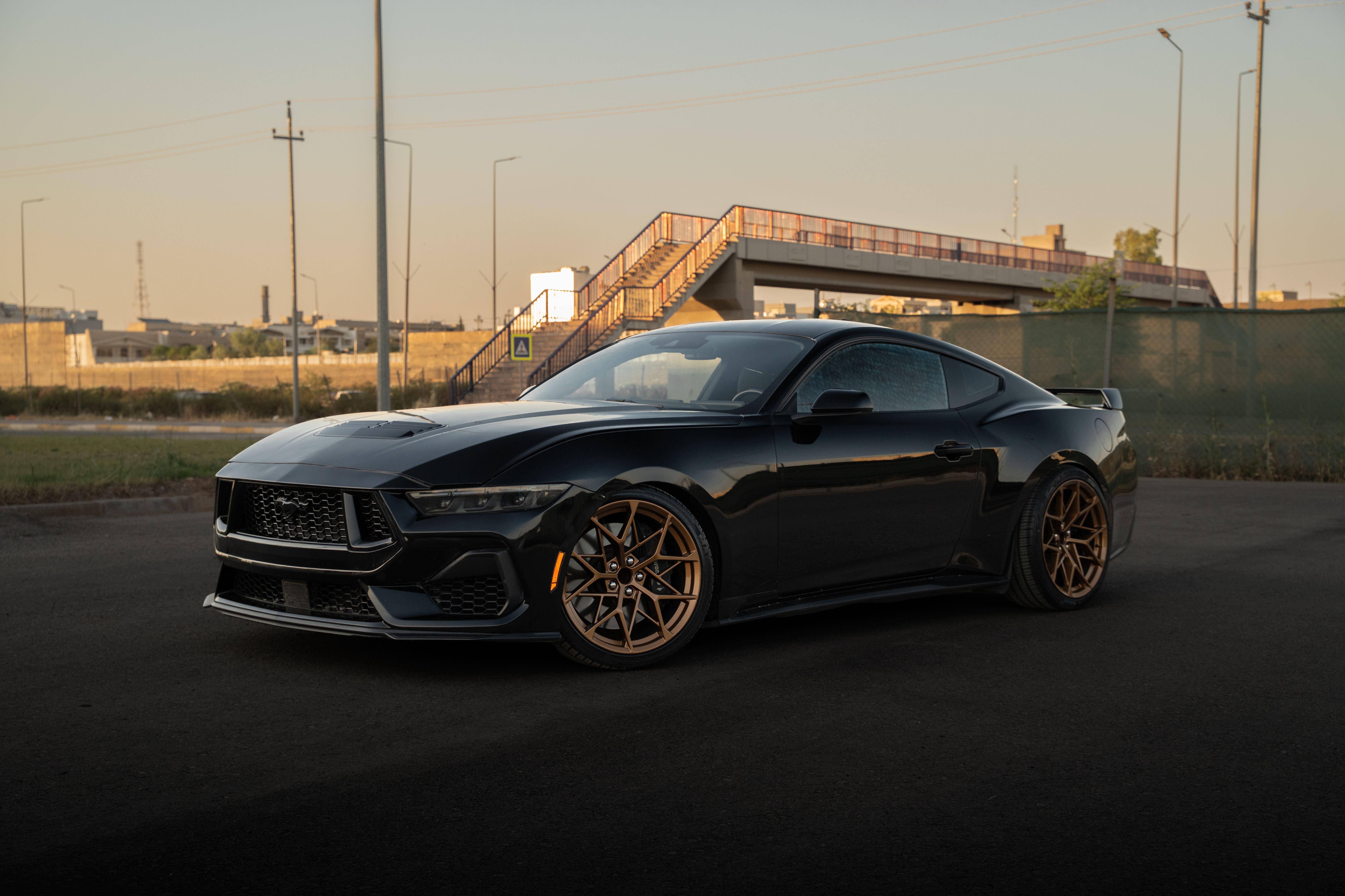 A modern black sports car parked on a city street at sunset, showcasing urban elegance.