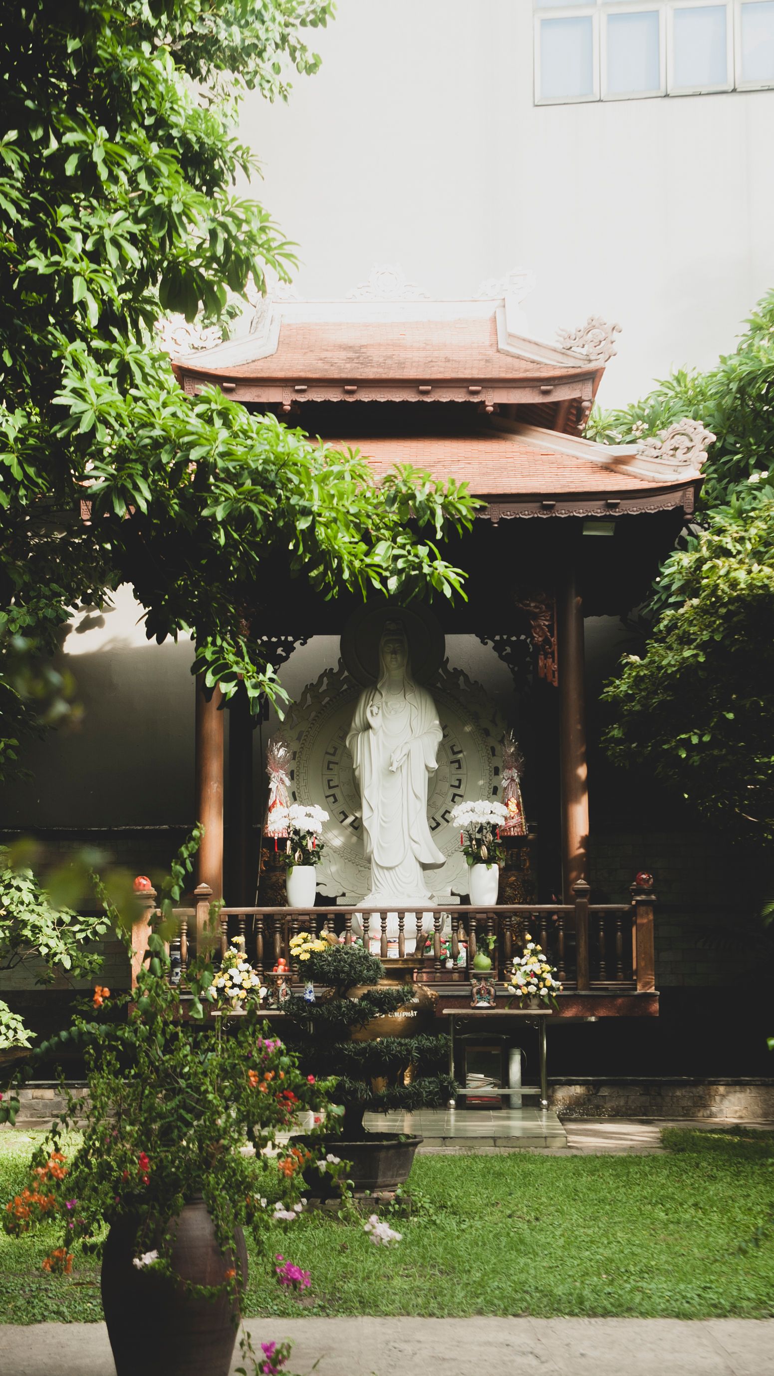 Peaceful Buddha statue surrounded by vibrant greenery in a tranquil Vietnamese garden setting.