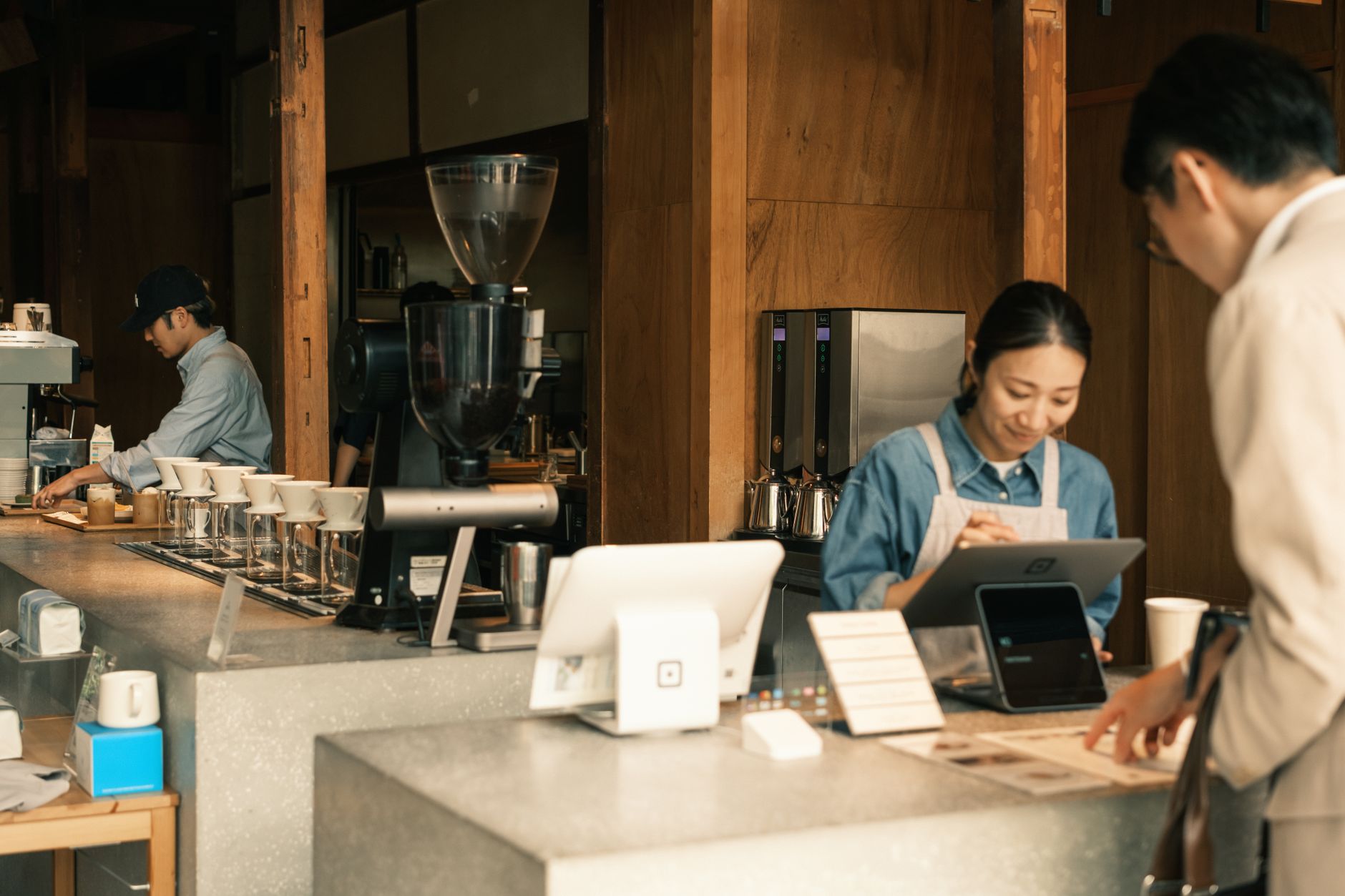 Barista and customers in a cozy Japanese coffee shop, showcasing a modern cafe atmosphere.