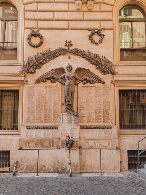 Free Winged angel statue on a historic monument in Rome, Italy, framed by architectural elements. Stock Photo