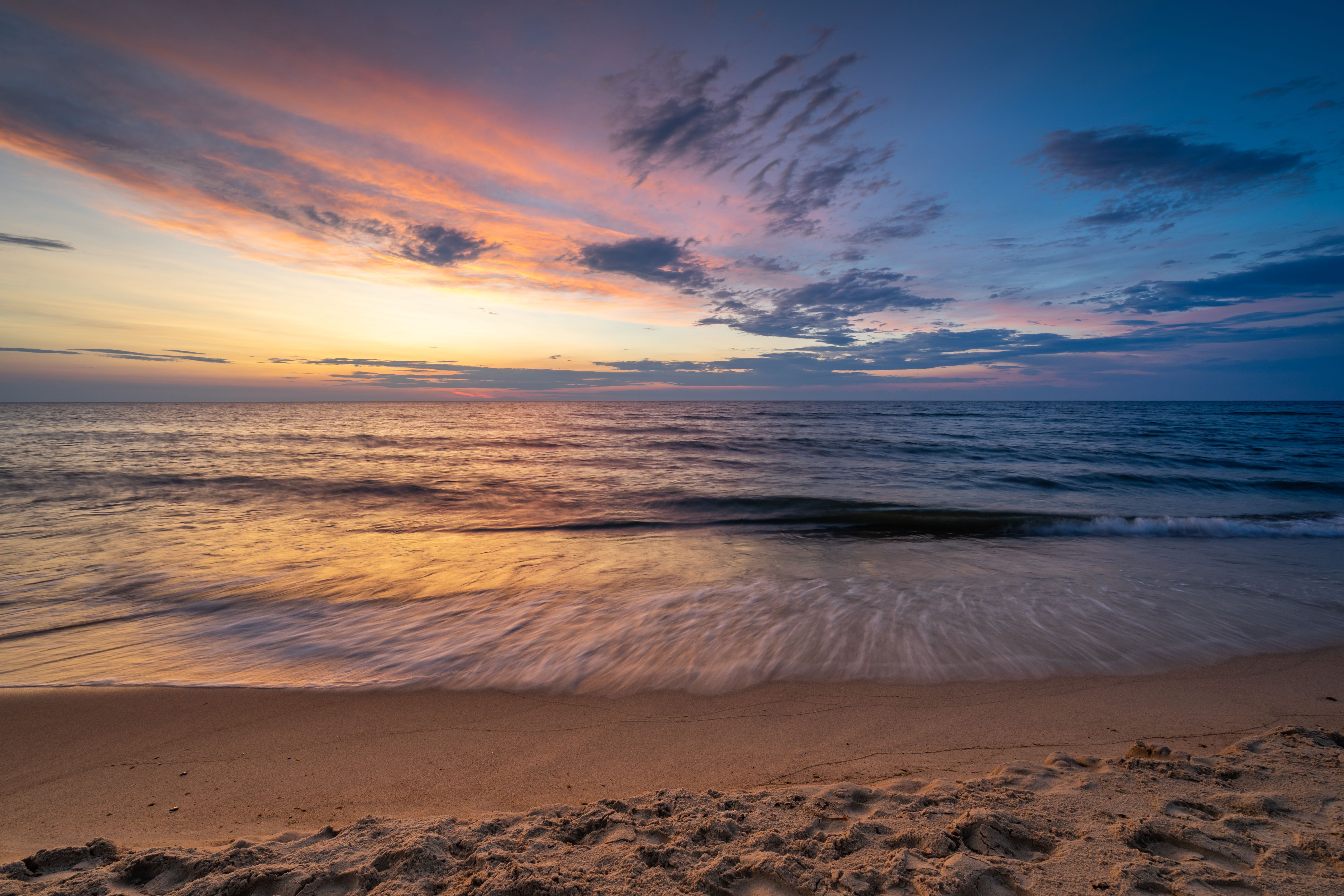 A breathtaking sunset over the Baltic Sea with vivid colors and gentle waves softly washing ashore on a sandy beach. — Trójmiasto