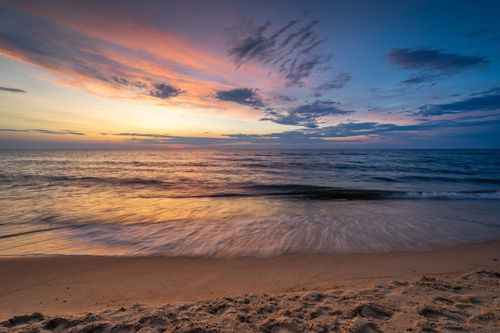 Free A breathtaking sunset over the Baltic Sea with vivid colors and gentle waves softly washing ashore on a sandy beach. Stock Photo