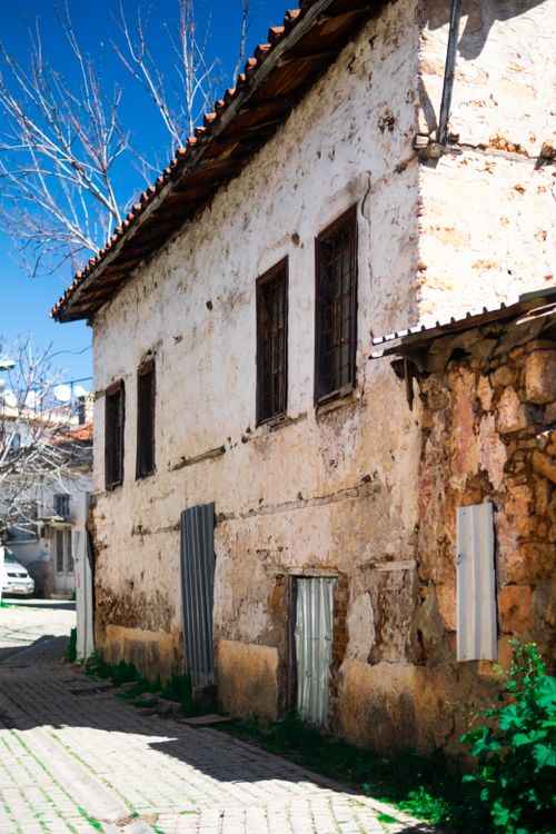 Free Weathered stone house facade with rustic architecture under a clear blue sky. Stock Photo