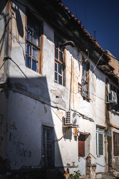 Free Old weathered building with peeling paint and contrasting sunlight creates a vintage appeal. Stock Photo
