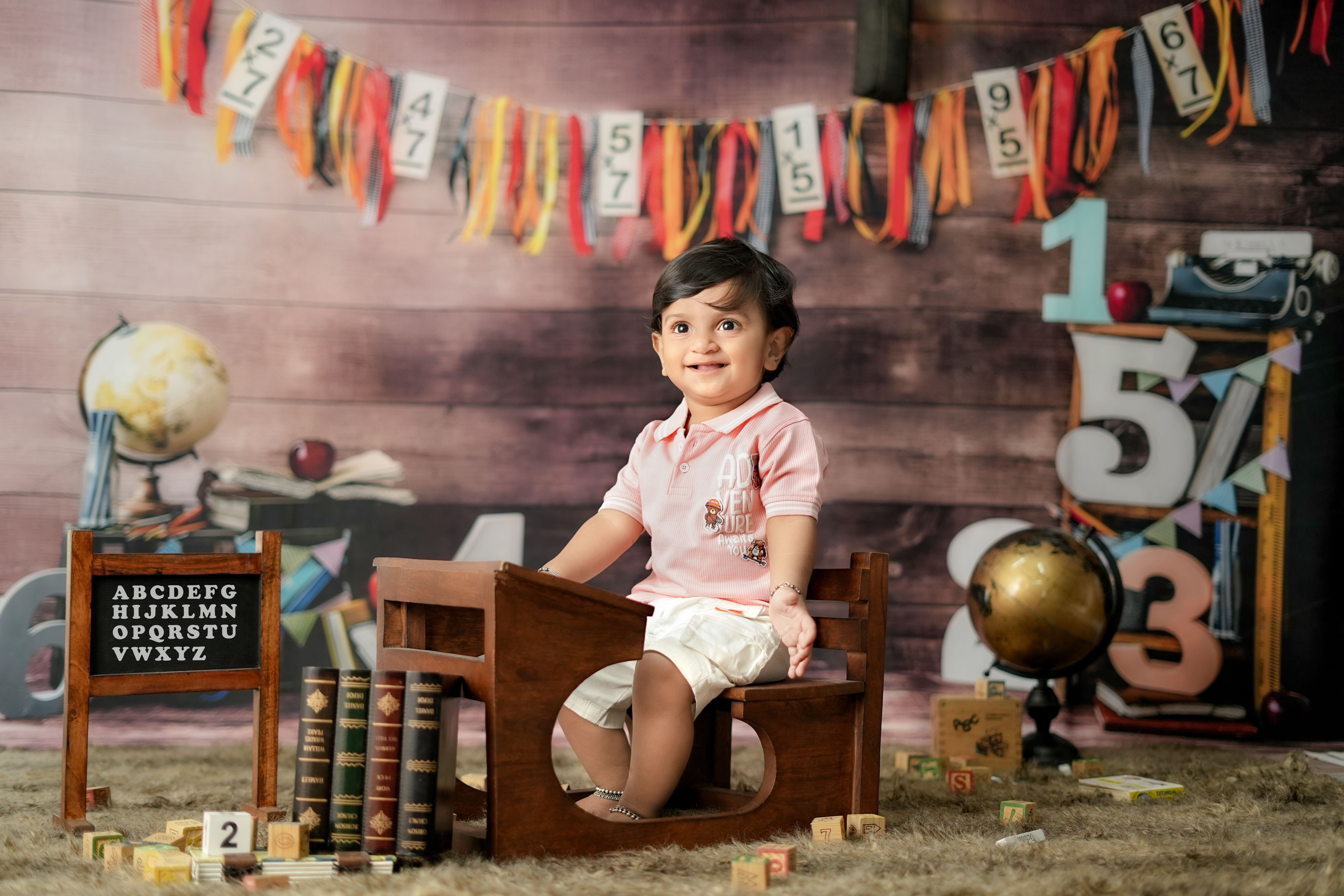 Adorable child sitting in a creative educational setting with books and globes, symbolizing learning and exploration.