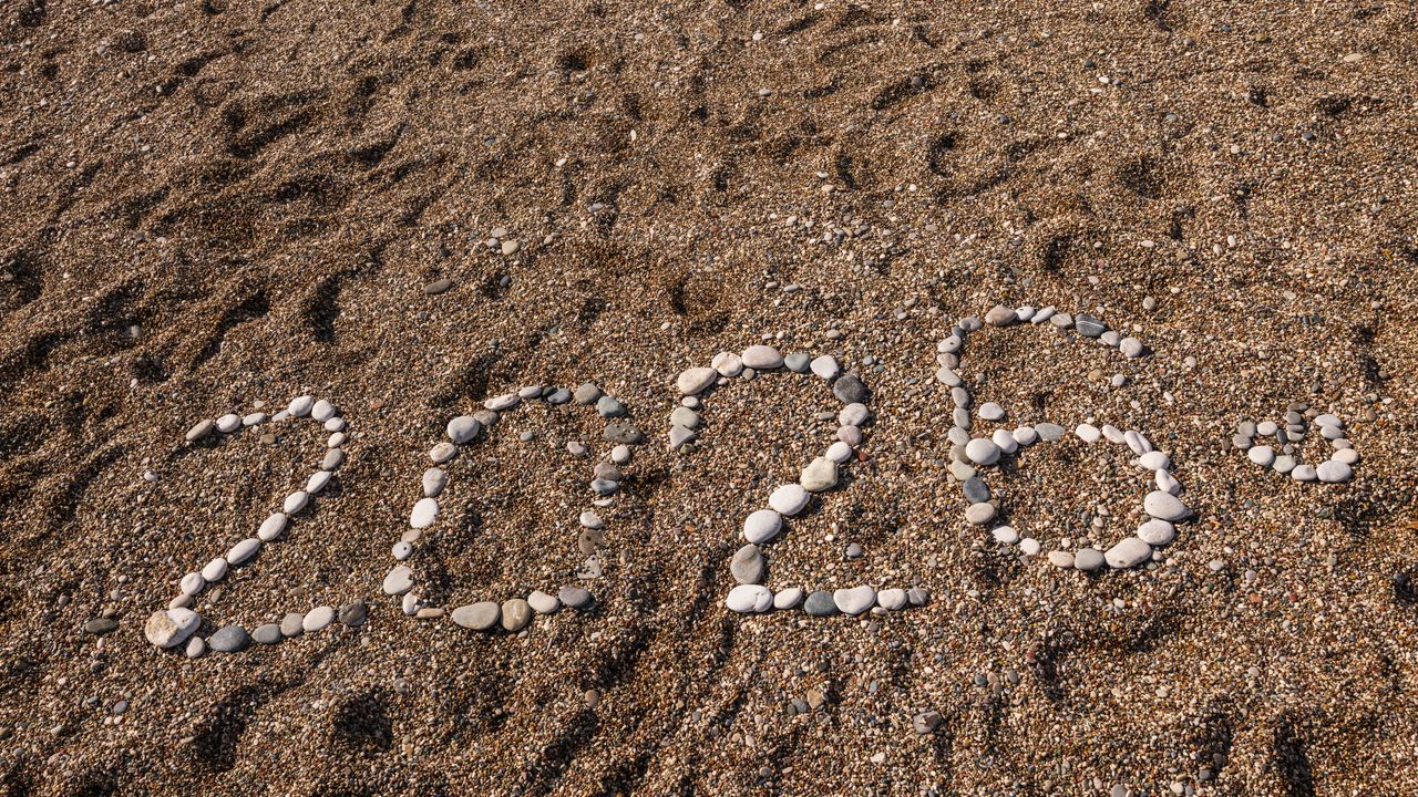 Stones arranged to form the number 2026 on a sandy coastline, creating a natural and creative scene.
