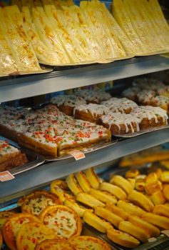 A tempting selection of pastries and pizza slices in a bakery display case.