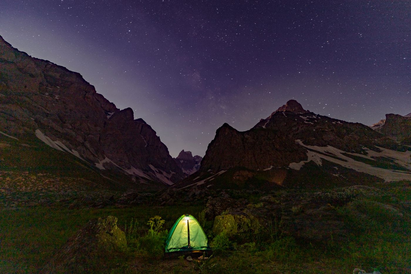 Glowing tent beneath starry mountain skies