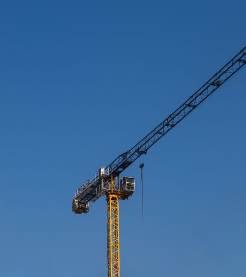 Free A tower crane stands tall against a vibrant blue sky, epitomizing urban growth in İzmir. Stock Photo