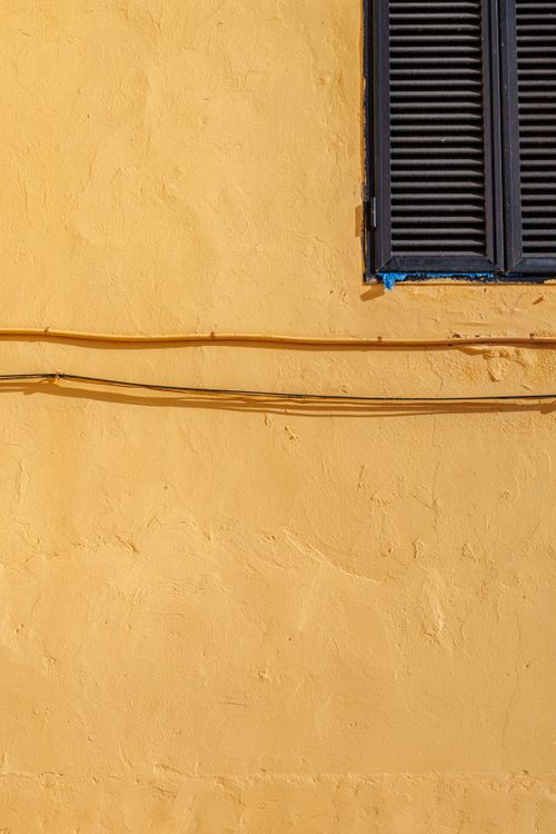 Free A vibrant yellow wall with a black shutter in Las Palmas, Spain. Stock Photo