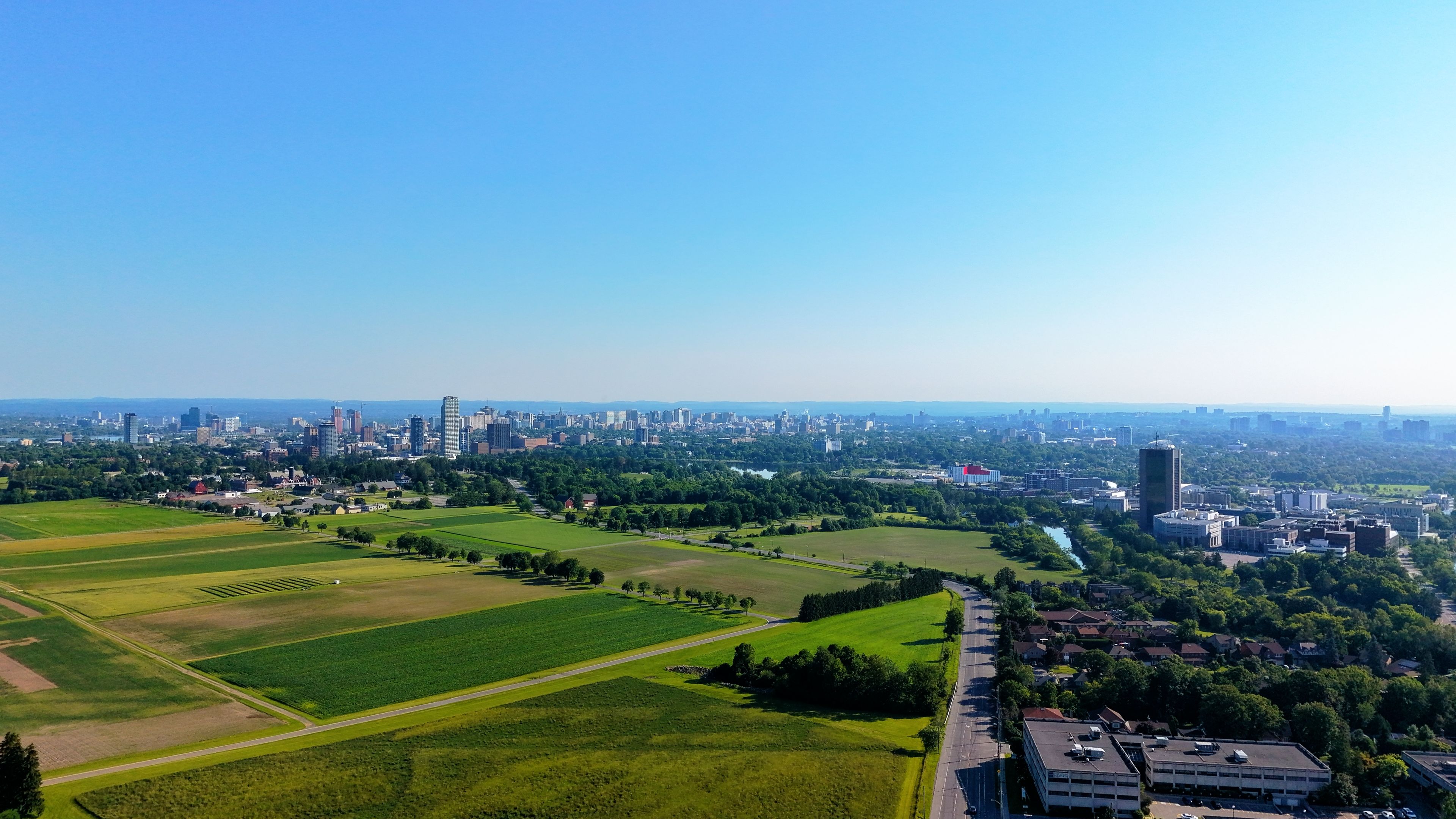 Ultimate Niagara Falls Grand Helicopter Adventure Review: Soaring Above One of Nature's Greatest Wonders Review 2026 - Aerial view of city skyline surrounded by lush green fields under clear blue sky.