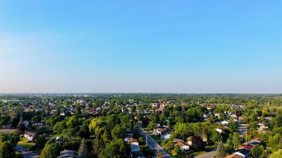 Ultimate Helicopter Tour Over Mont-Tremblant 70KM ( 20 min ) Review: Soaring Above Quebec's Most Stunning Mountain Resort Review 2026 - An expansive aerial view of a green suburban neighborhood under a clear blue sky.