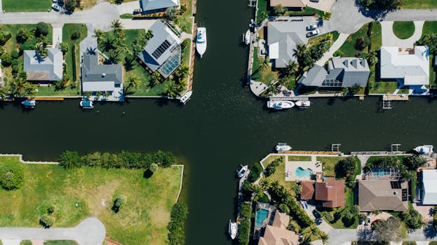 Aerial view of a scenic waterfront neighborhood with houses and boats along the canal on a sunny day.
