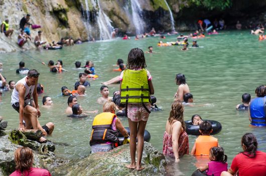 People enjoying a sunny day swimming by waterfalls in Tanay. Vibrant and lively outdoor scene.