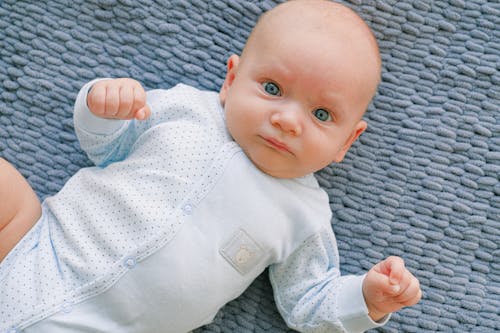 Bebé En Mono Blanco Acostado Sobre Textil Gris