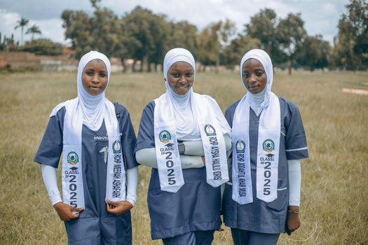 Three young women in hijabs posing outdoors, celebrating graduation with class of 2025 sashes.