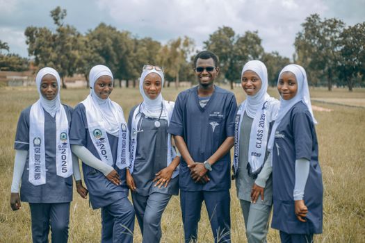 A group of smiling medical students in uniforms posing outdoors, showcasing diversity and teamwork.
