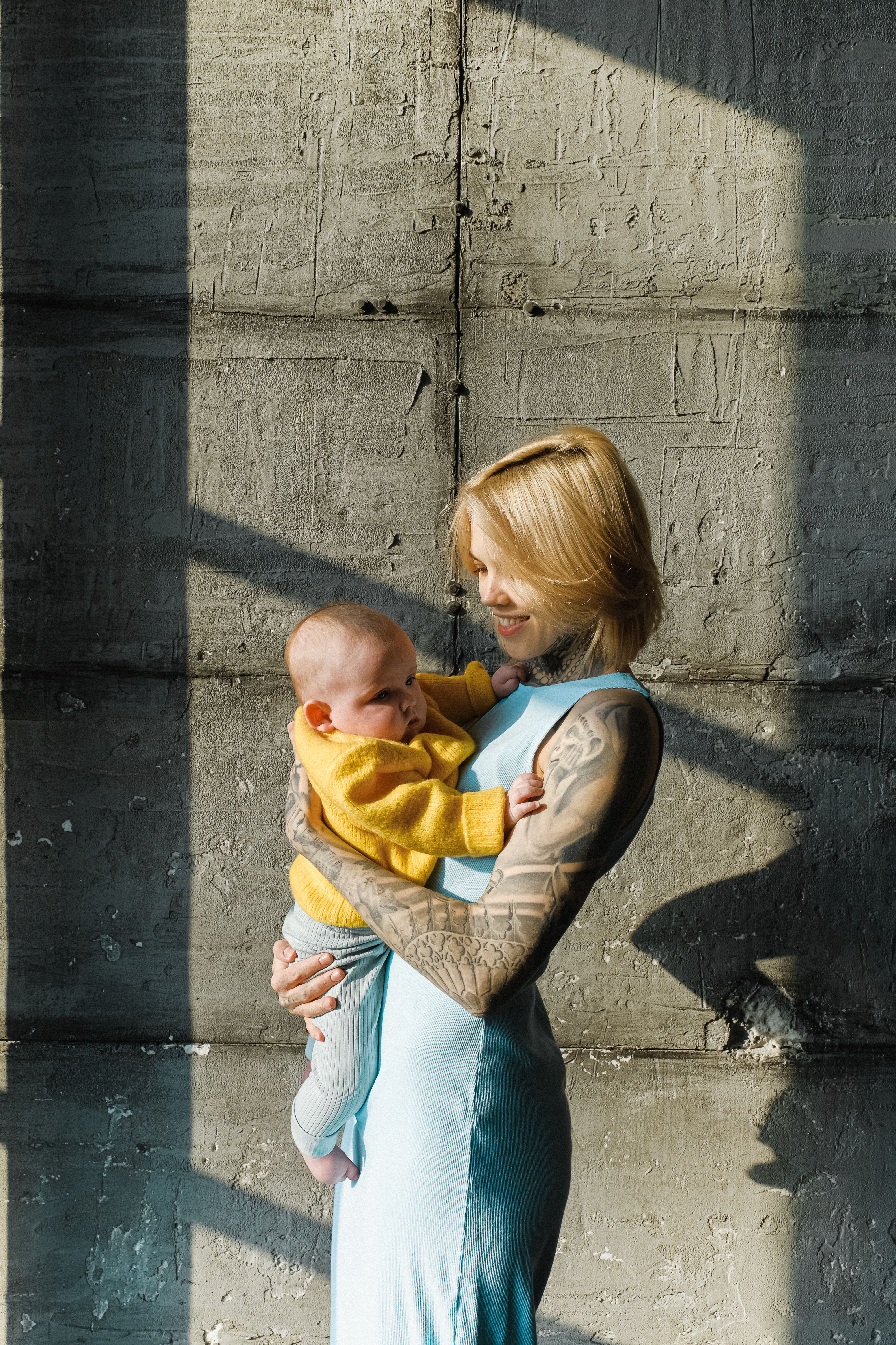 Loving mother with newborn baby near concrete wall · Free Stock Photo