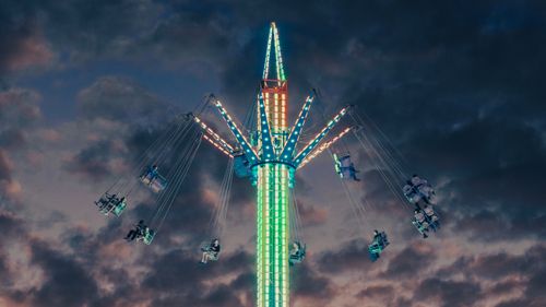 Free High-flying swing ride illuminated against a dramatic evening sky in Townsville, Australia. Stock Photo