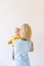 Tattooed mother hugging little baby isolated on gray background in studio