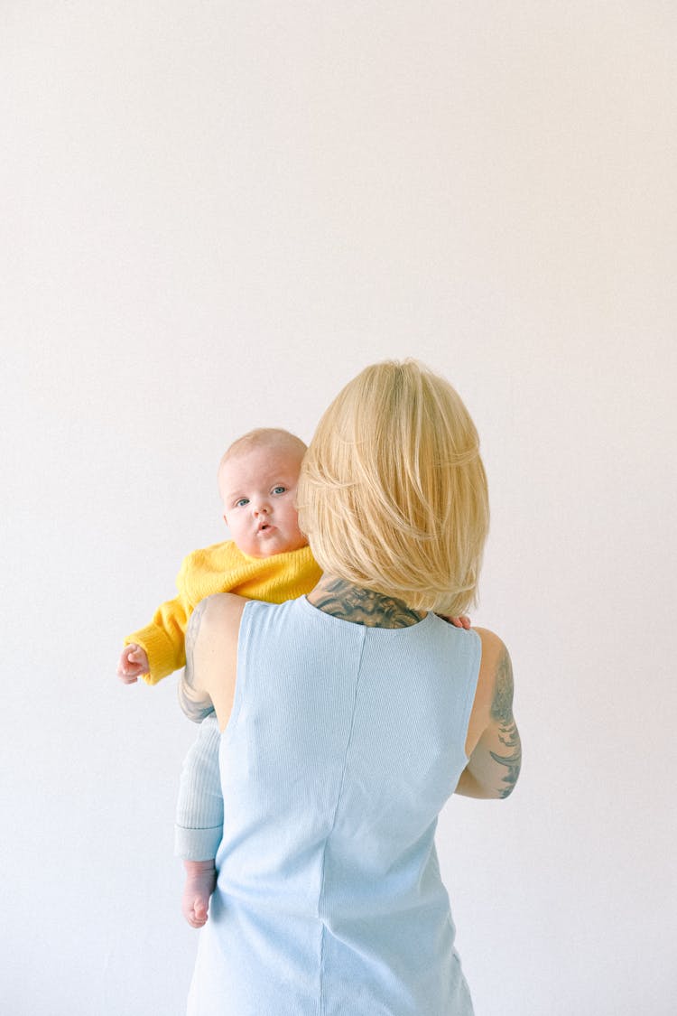 Tattooed Mother Hugging Little Baby Isolated On Gray Background In Studio