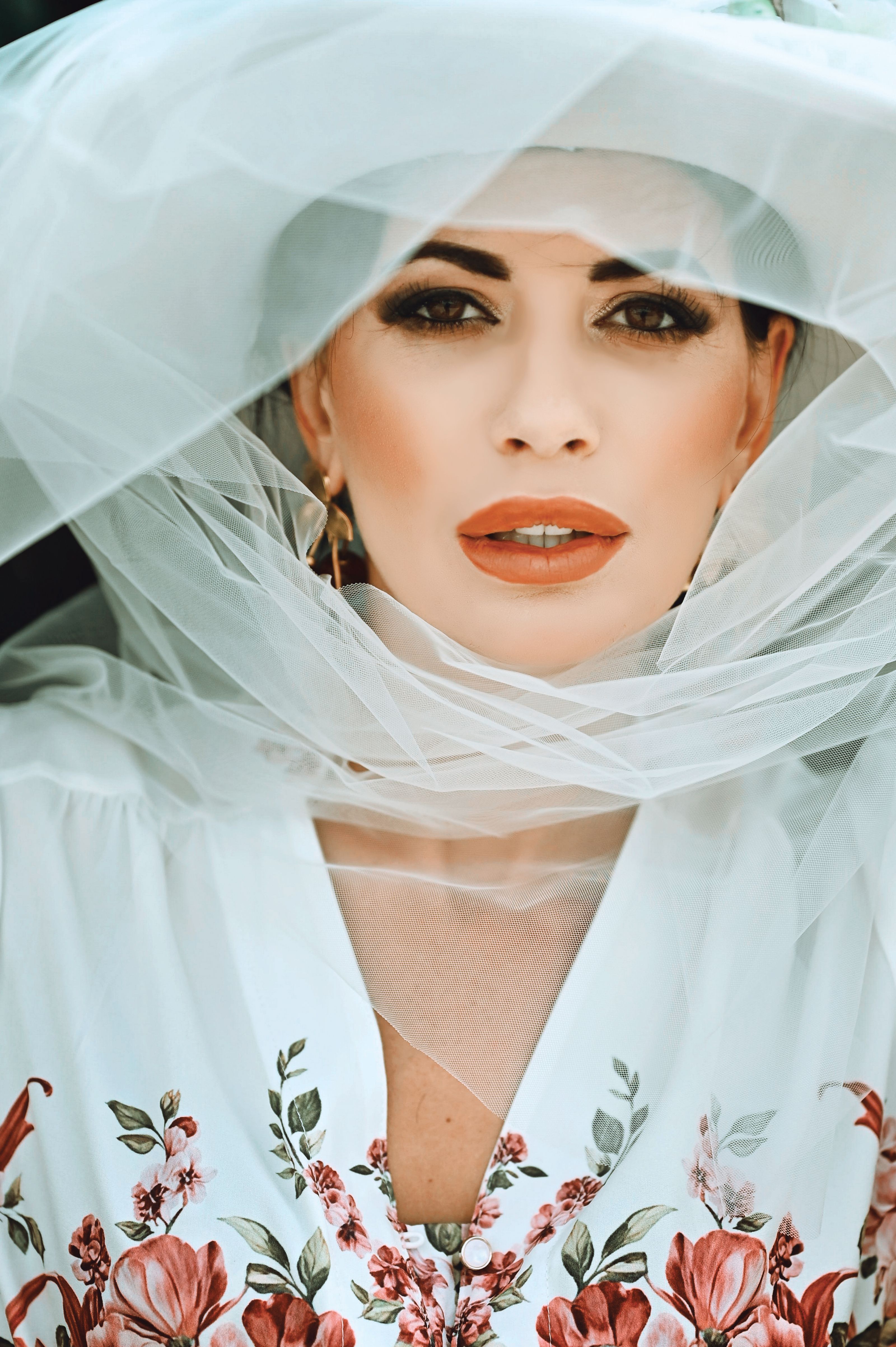 Retrato de uma mulher com vestido floral e véu, exalando elegância e estilo.