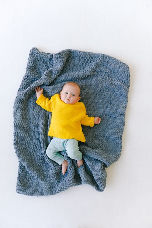 Free Adorable newborn baby resting on soft blue plaid in studio Stock Photo