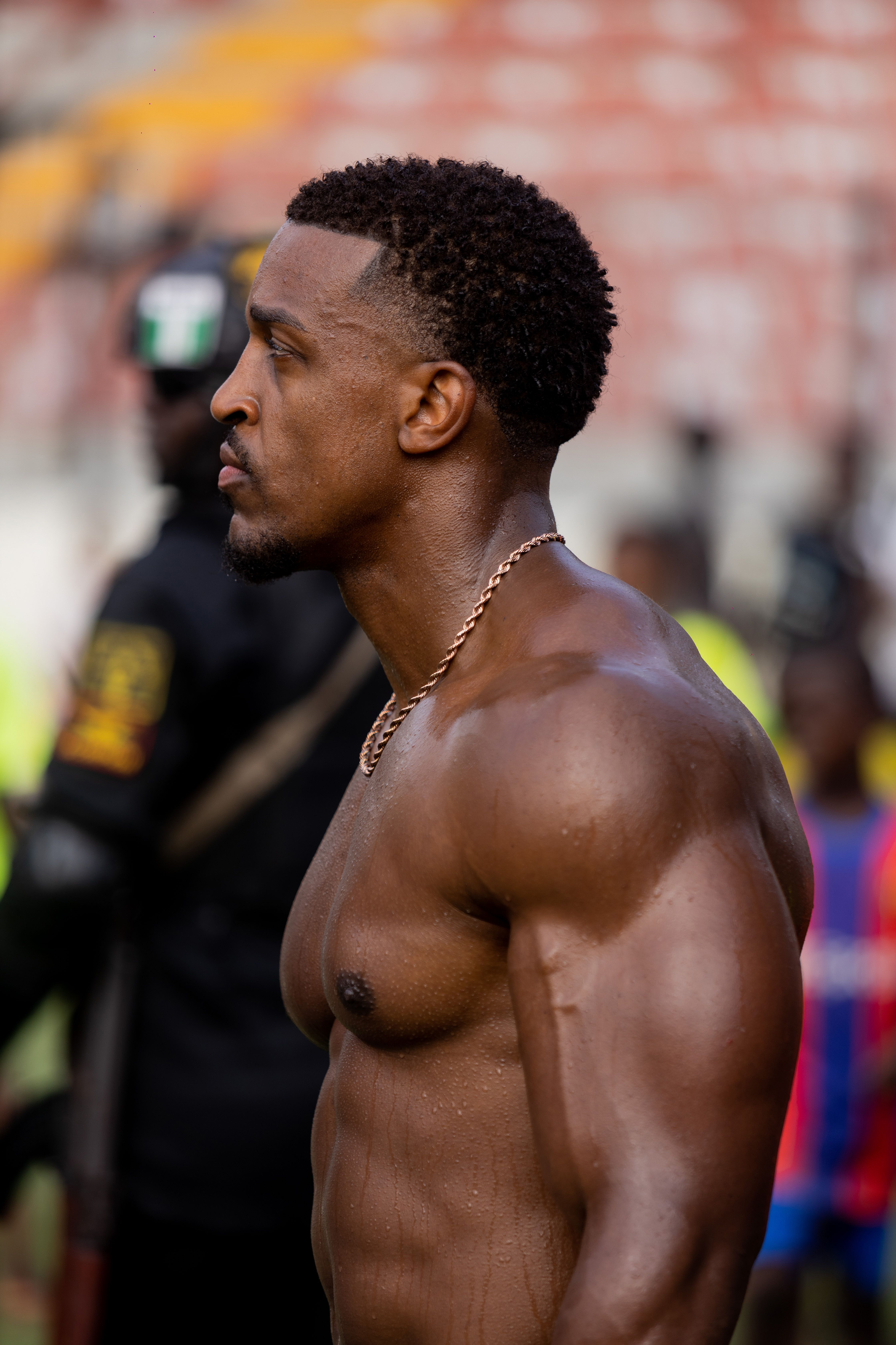 A muscular athlete with a focused expression stands outdoors, showcasing strength and readiness.