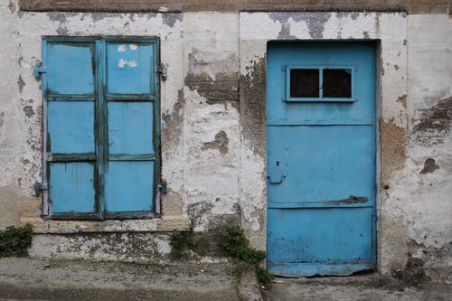 Free A weathered blue door and window on an old, textured wall in İzmir, Türkiye, showcasing rustic charm. Stock Photo