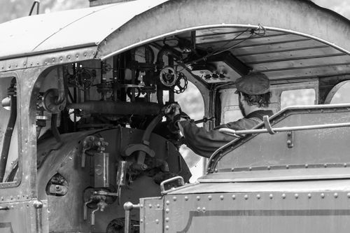 Free A vintage train engineer works in the steam locomotive's cabin, captured in black and white. Stock Photo