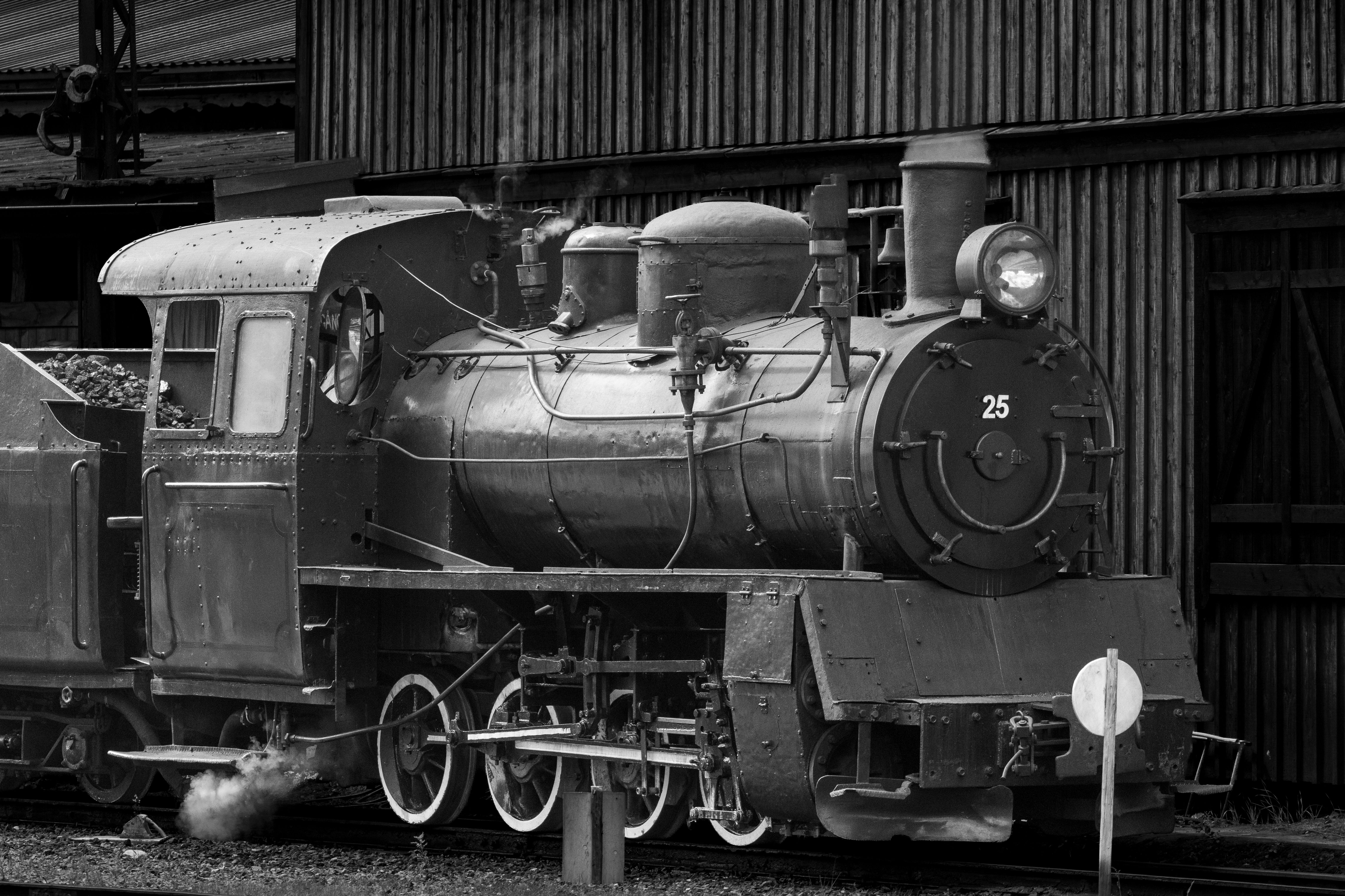 Black and white image of a historic steam train engine at a station.