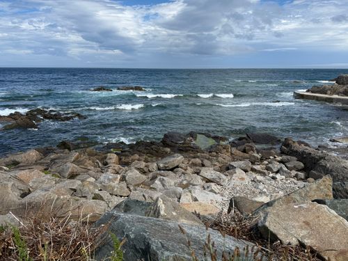 Free Breathtaking rocky seaside view in Howth, Ireland with a dramatic cloudy sky and waves crashing on the rocks. Stock Photo
