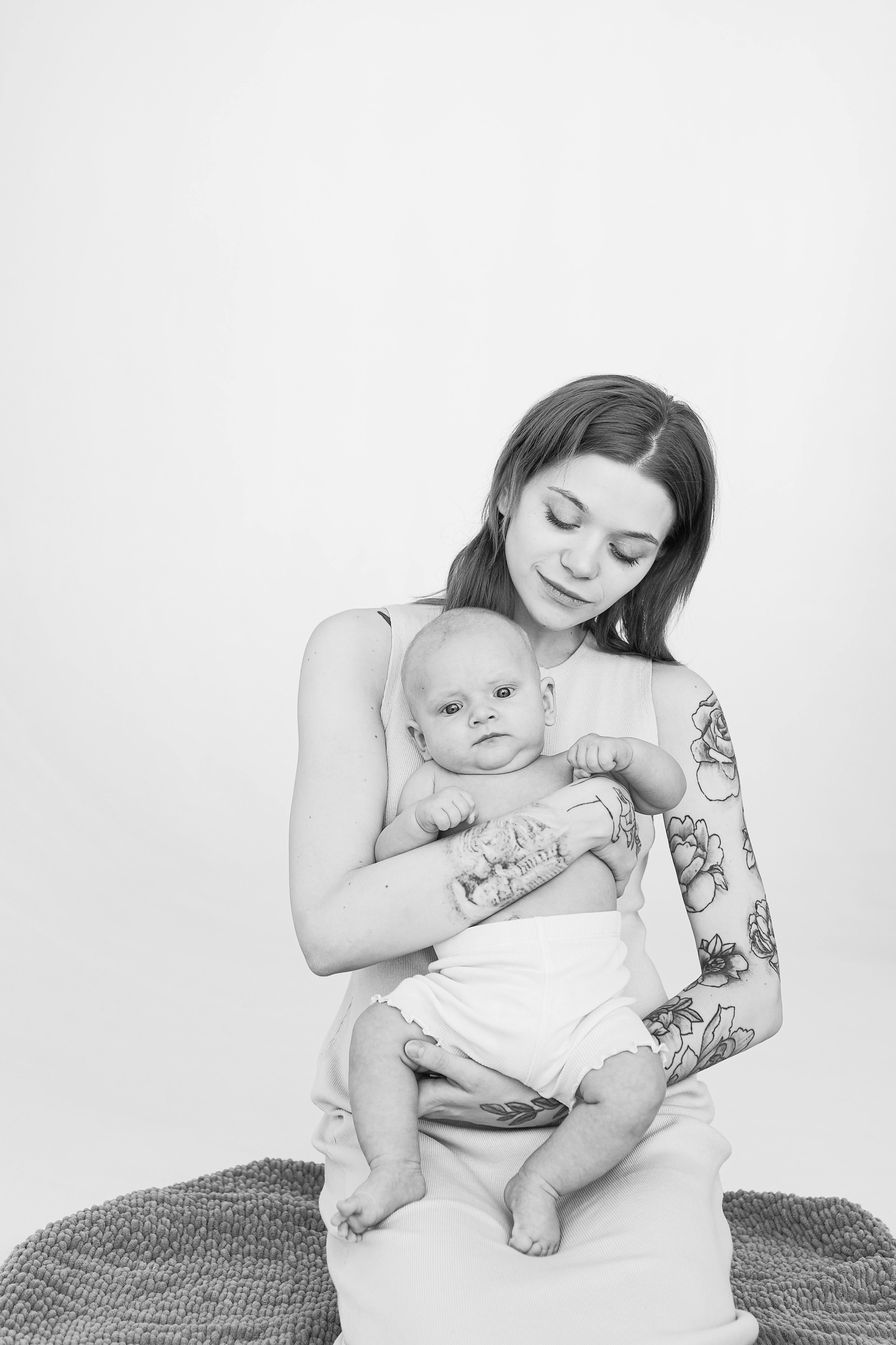 monochrome photo of tattooed mother carrying her cute baby